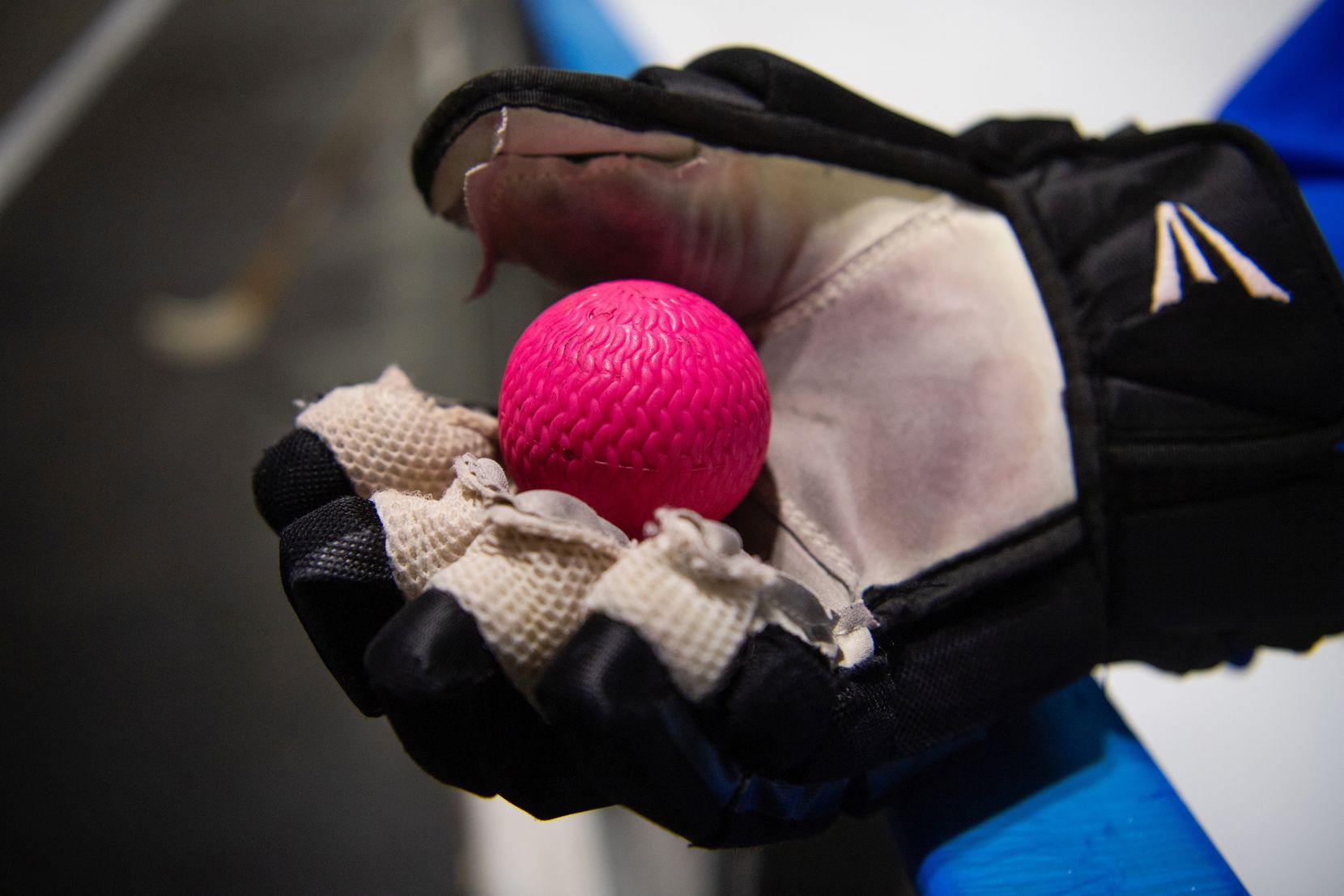 Ein pinker Ball liegt auf einem dicken Handschuh.